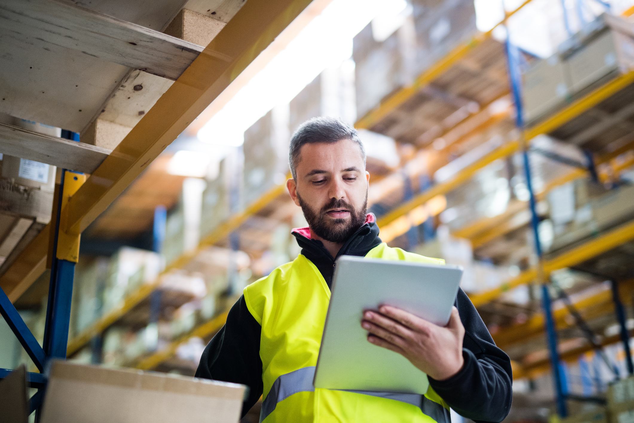 Young male warehouse worker with tablet, checking something.