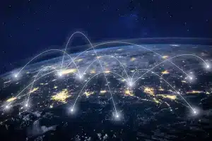 The Earth, viewed from space at night, shows glowing city lights connected by white arcs, symbolising global communication networks beneath a starry sky.