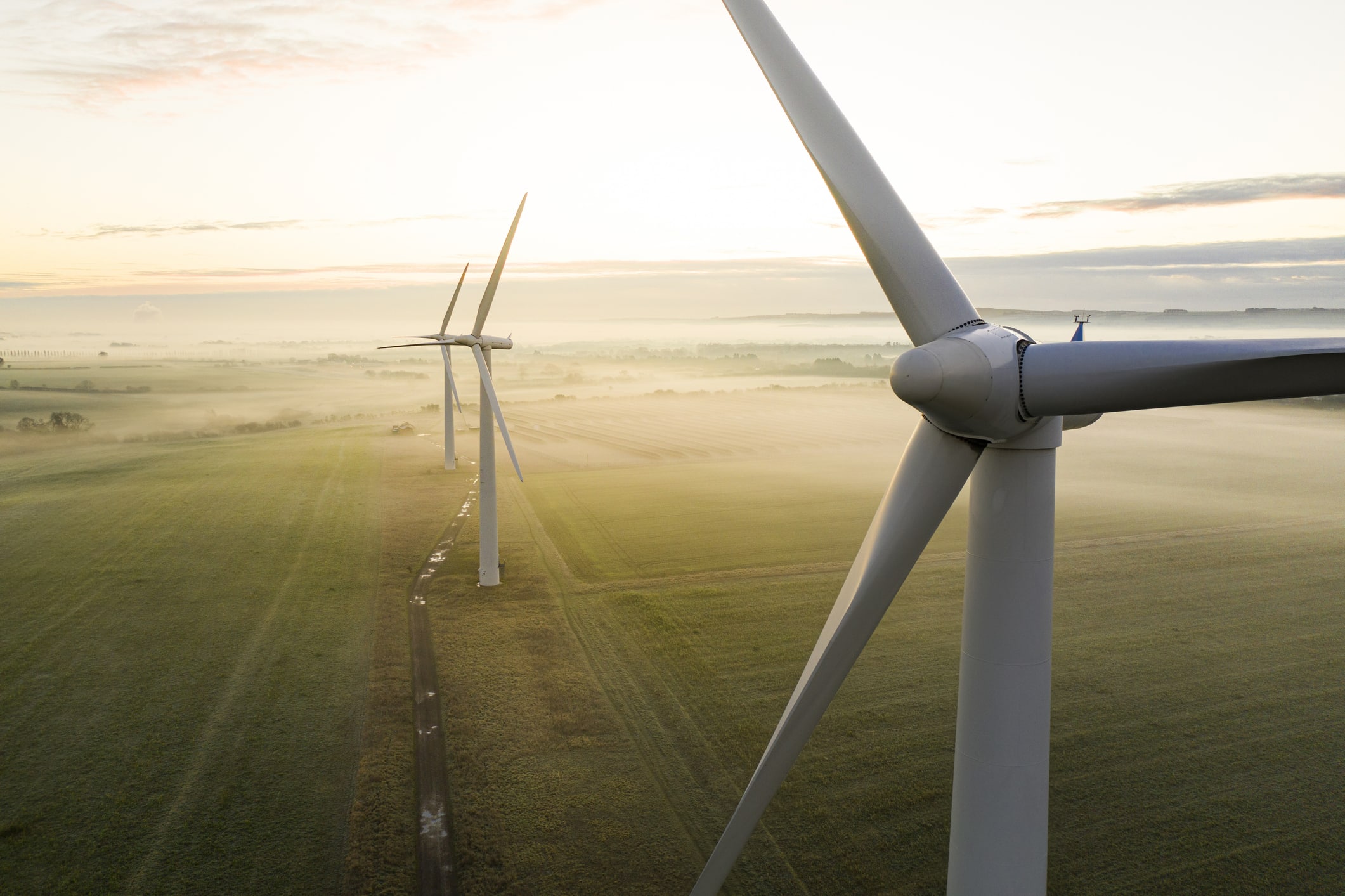 Wind turbines producing energy in a field on a misty day