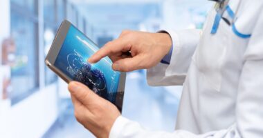 A Healthcare Professional Examines Information On A Digital Tablet In A Bright, High-tech Medical Facility, Focusing On Patient Data Analysis.
