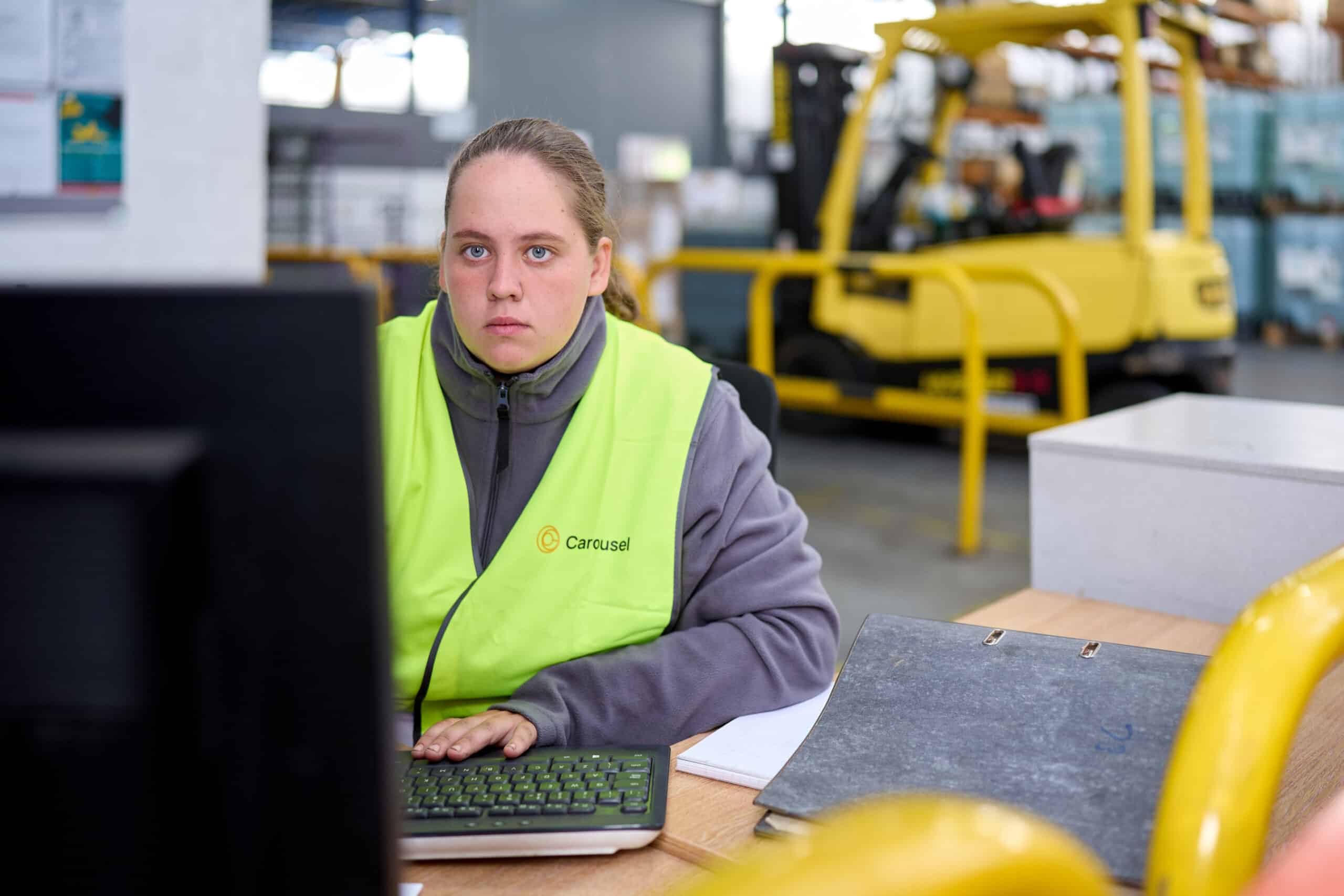 Woman working at computer in a warehouse environment